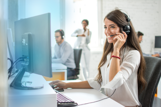 Freundliche Dame mit Headset am Telefon.
