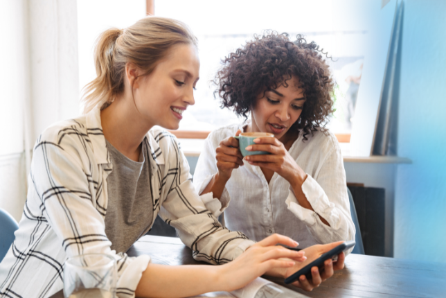 Eine Frau zeigt einer anderen Frau etwas auf einem Smartphone.