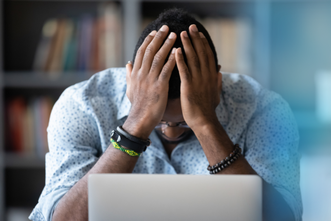 Mann vor Laptop schl&auml;gt H&auml;nde &uuml;ber dem Kopf zusammen.