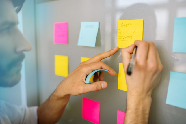 Mann beschriftet gelbes Post-It